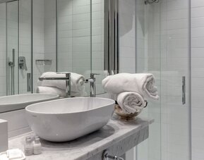 Bathroom featuring a marble vanity, vessel sink, glass-enclosed shower, and modern fixtures at Cellai Boutique Hotel.