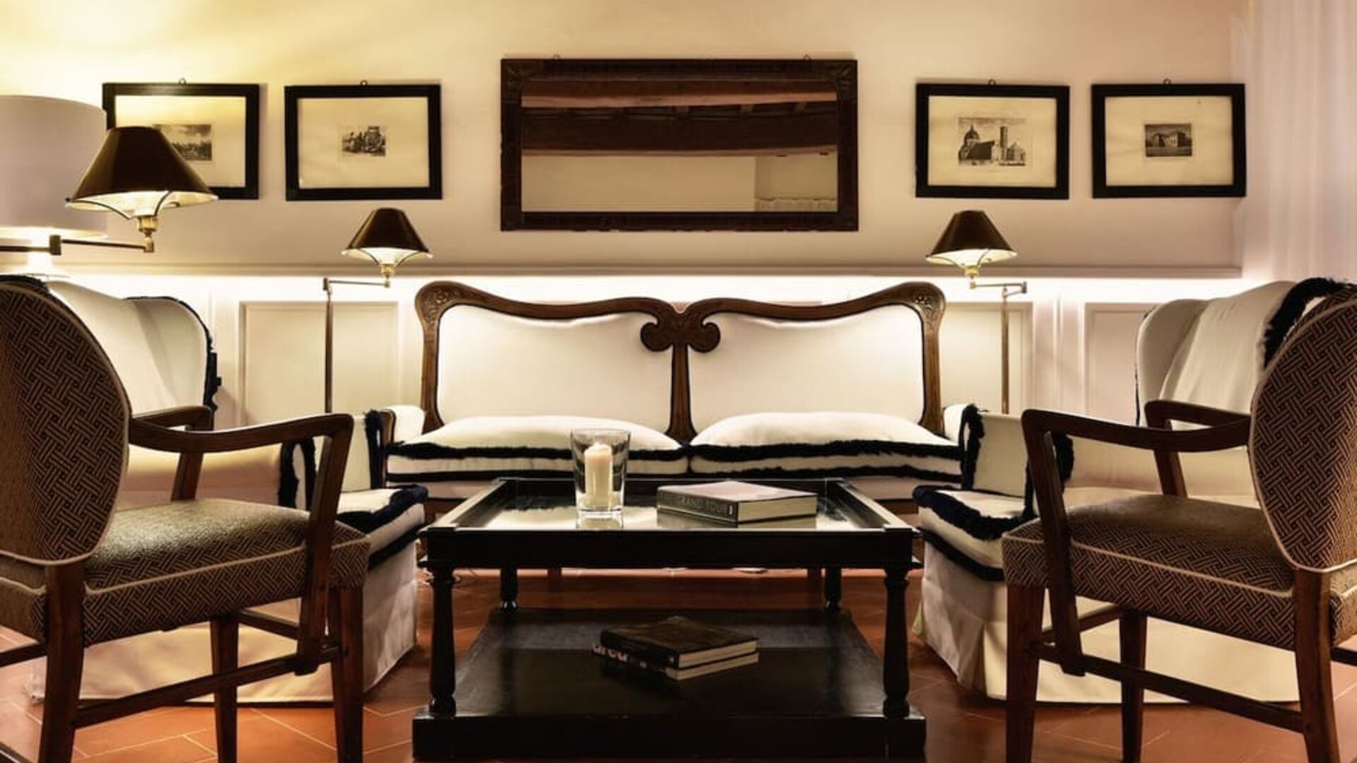 Seating area featuring upholstered chairs, warm lighting, framed artwork, and a classic lounge setting at Cellai Boutique Hotel.