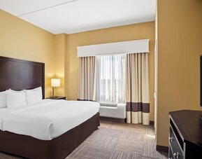 Guest room with a king-size bed, work desk, flat-screen television, and large window with blackout curtains at Comfort Suites Frisco.