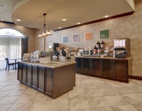 Complimentary breakfast area featuring hot breakfast stations, cereal dispensers, coffee service, and self-serve dining options at Comfort Suites Frisco.