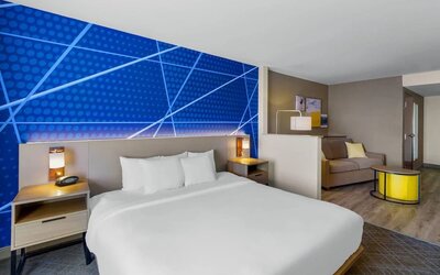 Spacious king suite featuring a king bed, separate sitting area with a sofa, and contemporary furnishings at Comfort Suites Vacaville-Napa Valley Area.