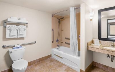 Accessible bathroom with a bathtub and shower combination, grab bars, spacious vanity, and fresh towels at Comfort Suites Vacaville-Napa Valley Area.