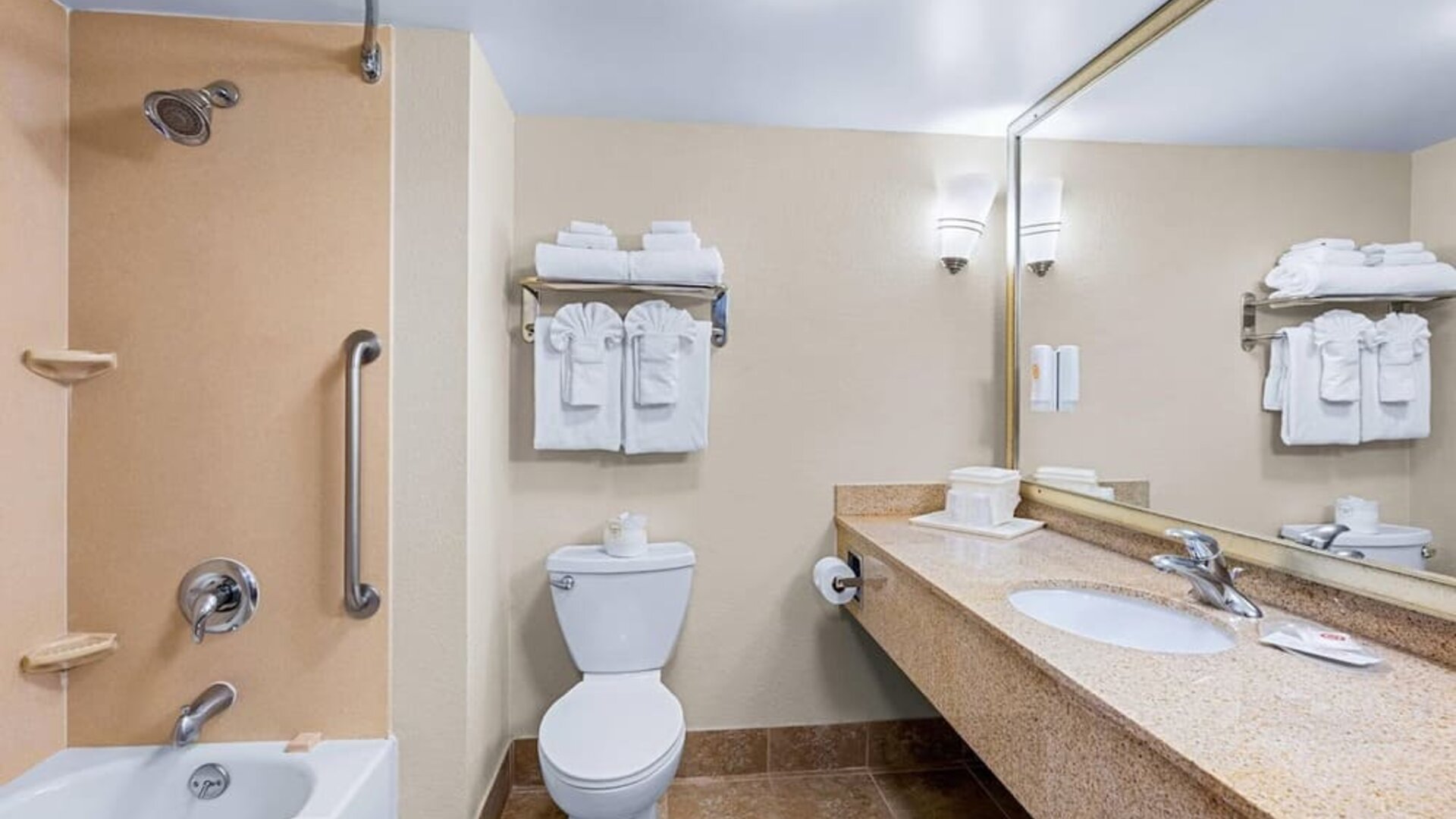 Guest bathroom featuring a bathtub and shower combination, granite vanity, large mirror, and fresh towels at Comfort Suites Vacaville-Napa Valley Area.