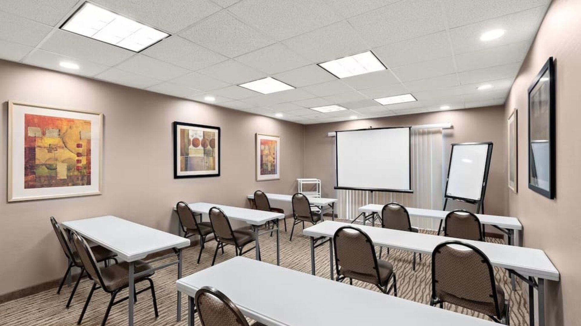Meeting room arranged with tables and chairs, a projection screen, and presentation equipment at Comfort Suites Vacaville-Napa Valley Area.