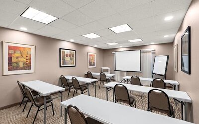 Meeting room arranged with tables and chairs, a projection screen, and presentation equipment at Comfort Suites Vacaville-Napa Valley Area.