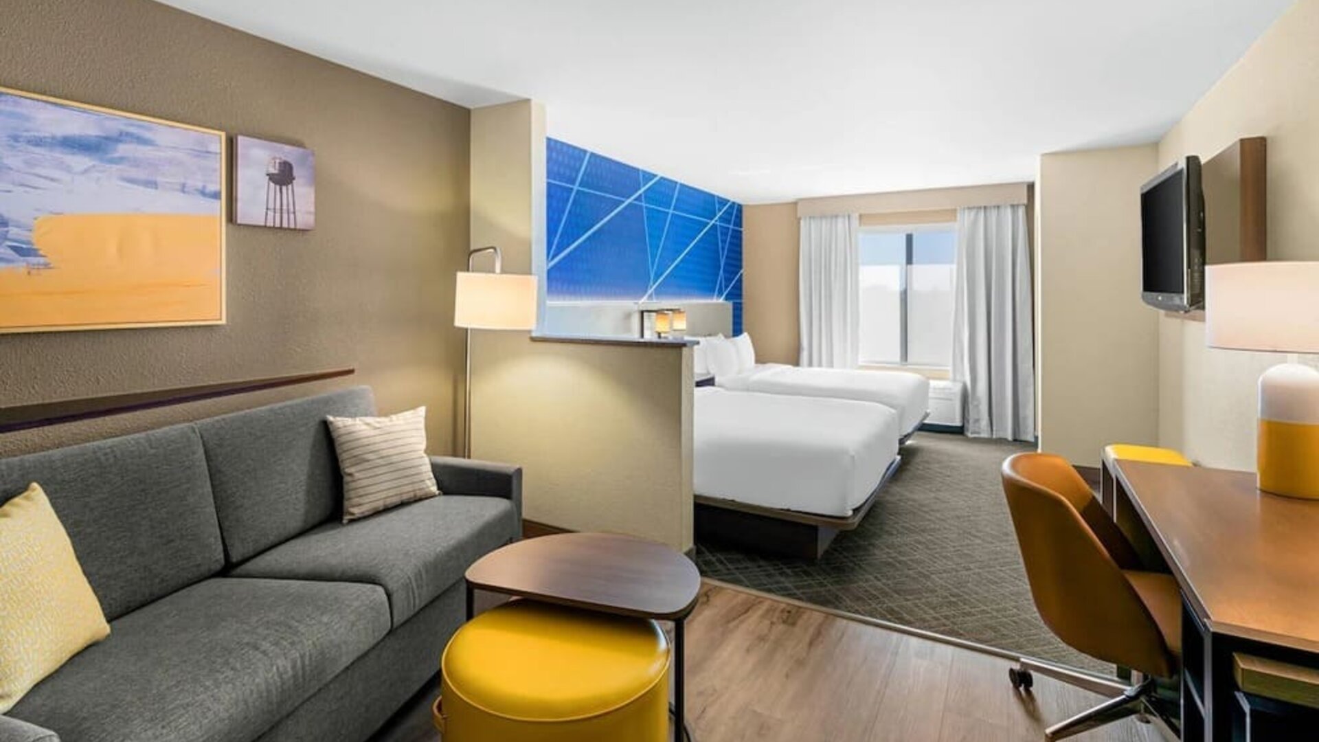 Spacious suite with two beds, a separate sitting area, sofa, workspace, and flat-screen television at Comfort Suites Vacaville-Napa Valley Area.