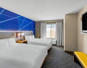 Guest room with two queen beds, modern blue accent décor, a flat-screen television, and natural light at Comfort Suites Vacaville-Napa Valley Area.