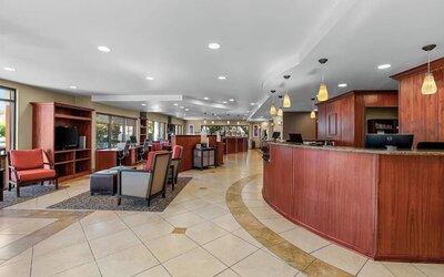 Spacious reception and lobby area featuring the front desk, guest seating, and warm pendant lighting at Comfort Suites Vacaville-Napa Valley Area.