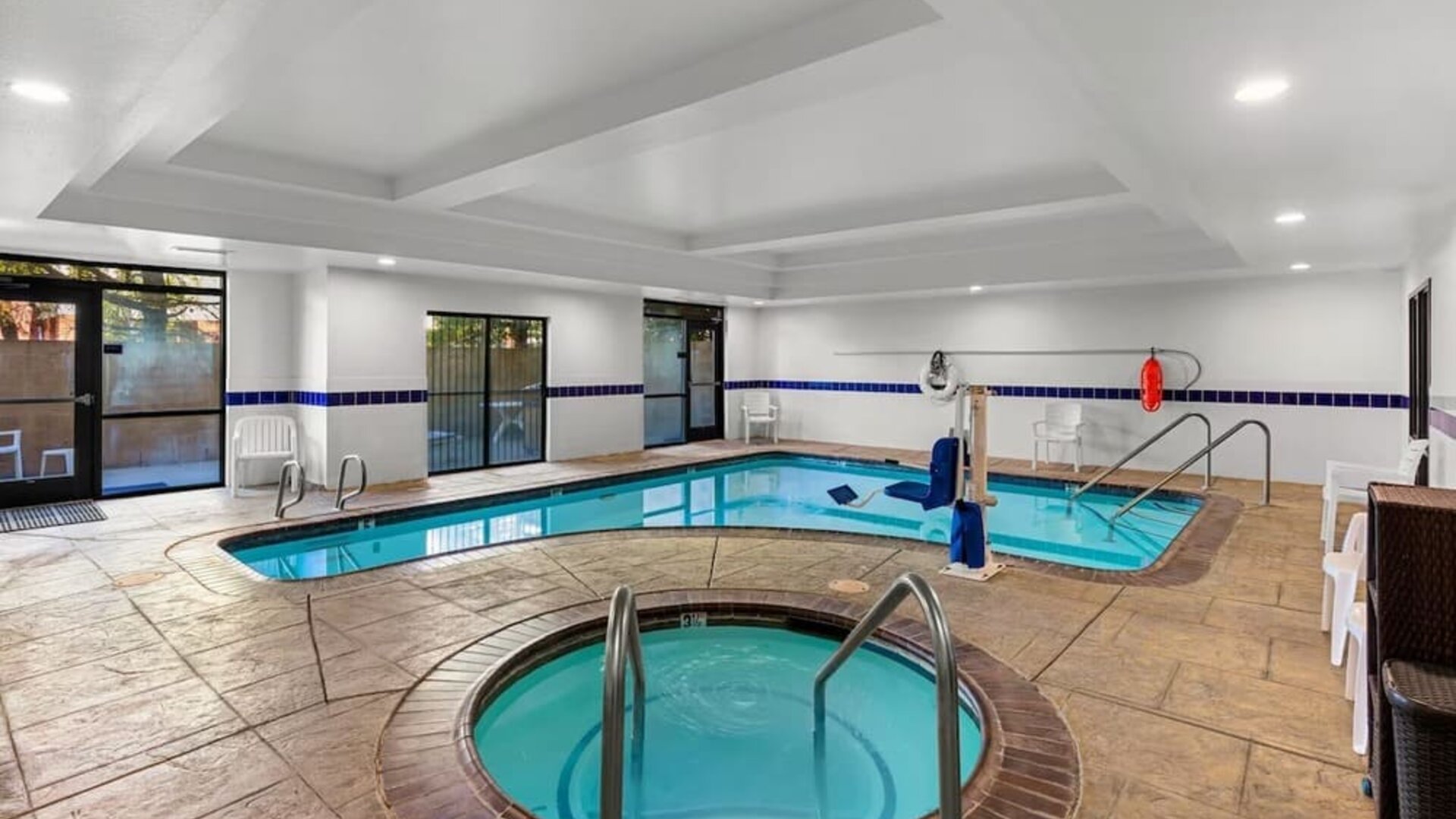 Indoor pool and hot tub area with poolside seating, handrails, and an accessible pool lift at Comfort Suites Vacaville-Napa Valley Area.
