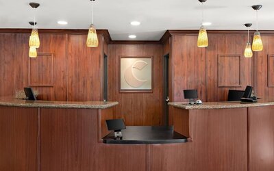 Front desk and reception area featuring granite counters, warm wood finishes, and pendant lighting at Comfort Suites Vacaville-Napa Valley Area.