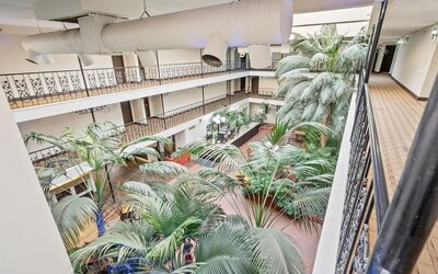 Interior atrium featuring lush tropical plants, open corridors, and decorative railings at Coratel Plus Suites Wichita West Airport.