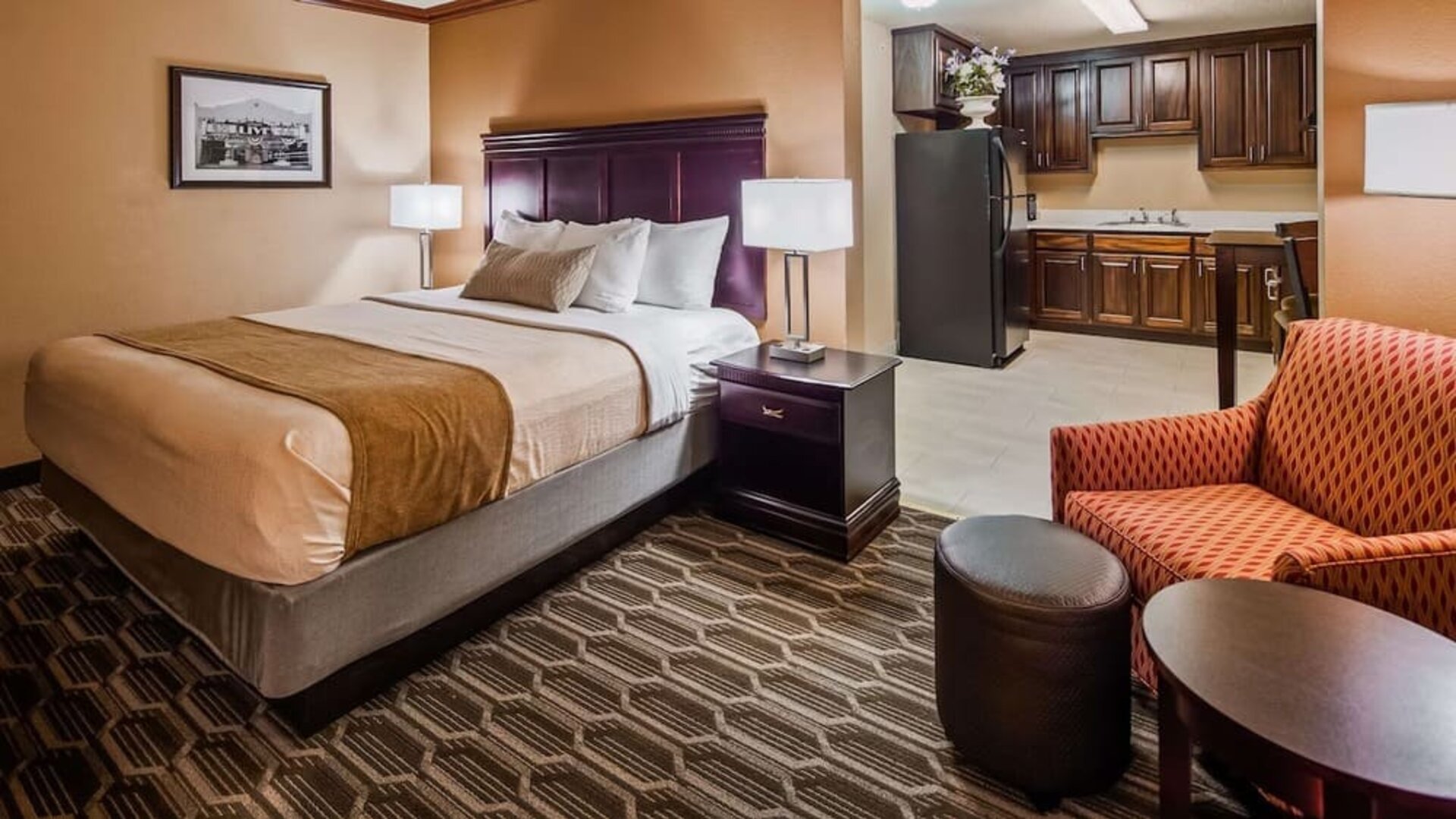 Spacious king guest room featuring a king bed, comfortable seating area, and kitchenette with refrigerator and cabinetry at Best Western Granbury Inn & Suites.