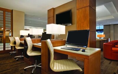 Business centre featuring multiple computer workstations, desk chairs, and individual task lighting at Hyatt Place San Jose Downtown.
