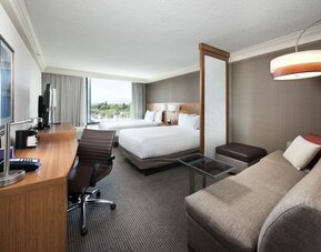 Accessible guest bathroom featuring a roll-in shower, grab bars, fold-down shower seat, and pedestal sink at Hyatt Place San Jose Downtown.  