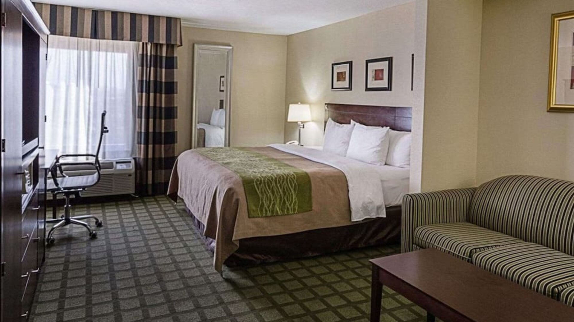 Spacious guest room featuring a king bed, sofa seating area, coffee table, workspace, and large window at Comfort Inn Southwest At Westpark.