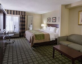 Spacious guest room featuring a king bed, sofa seating area, coffee table, workspace, and large window at Comfort Inn Southwest At Westpark.