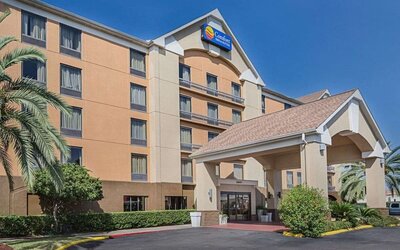 Exterior view of the multi-storey hotel featuring a covered entrance, landscaped grounds, and palm trees at Comfort Inn Southwest At Westpark.