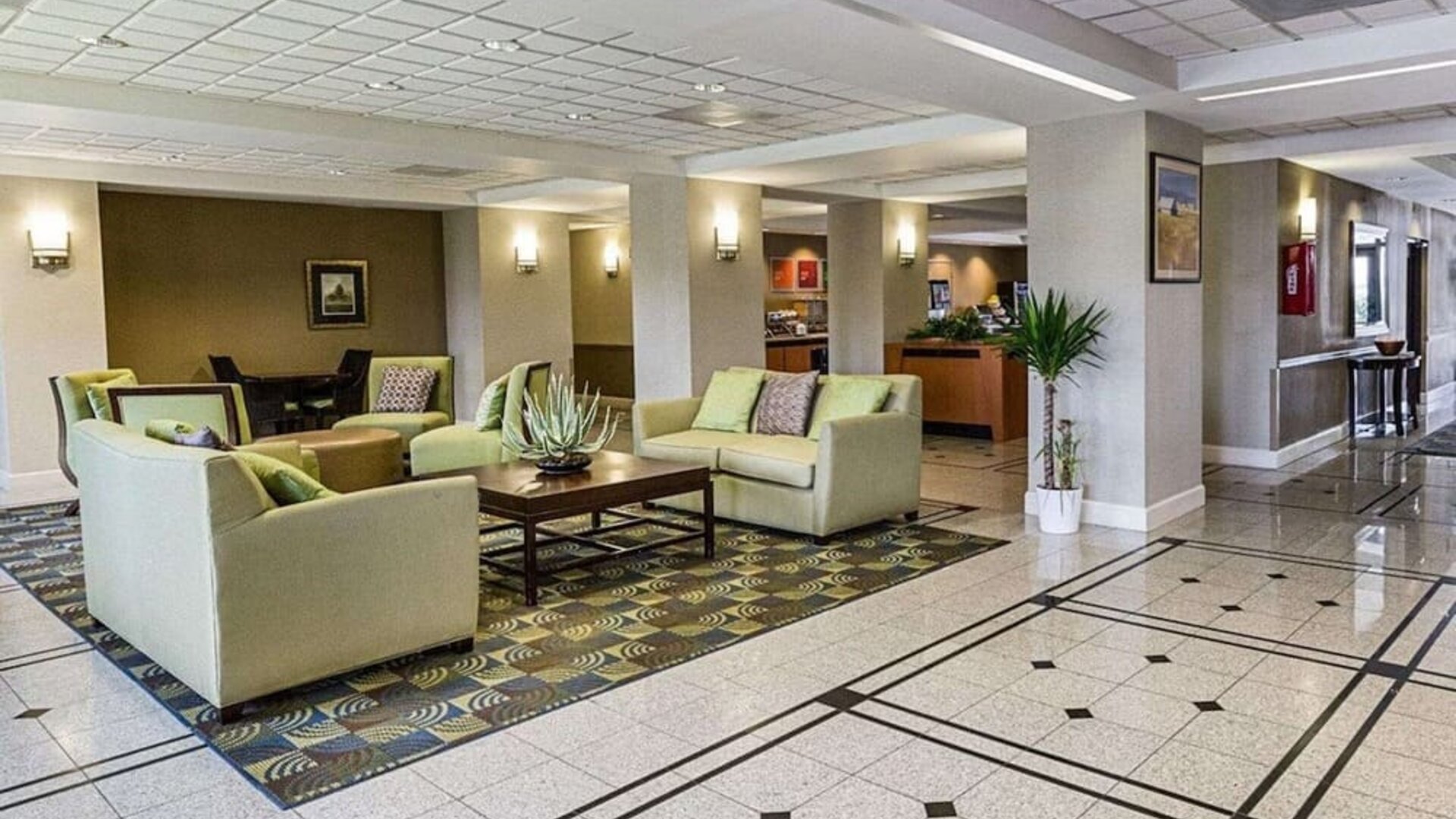 Spacious hotel lobby featuring sofas, armchairs, coffee tables, decorative plants, and tiled flooring at Comfort Inn Southwest At Westpark.