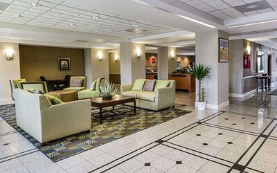 Spacious hotel lobby featuring sofas, armchairs, coffee tables, decorative plants, and tiled flooring at Comfort Inn Southwest At Westpark.