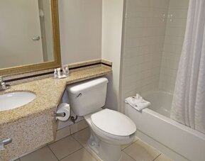 Guest bathroom featuring a granite vanity, large mirror, toilet, and bathtub with shower at Comfort Inn Southwest At Westpark.
