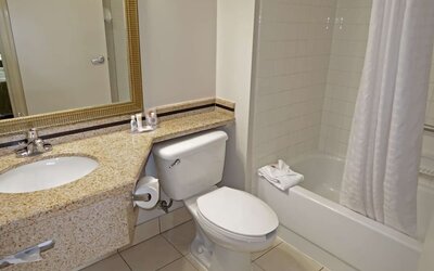 Guest bathroom featuring a granite vanity, large mirror, toilet, and bathtub with shower at Comfort Inn Southwest At Westpark.
