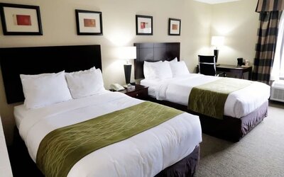 Guest room featuring two beds, bedside lighting, a work desk, chair, and large window at Comfort Inn Southwest At Westpark.