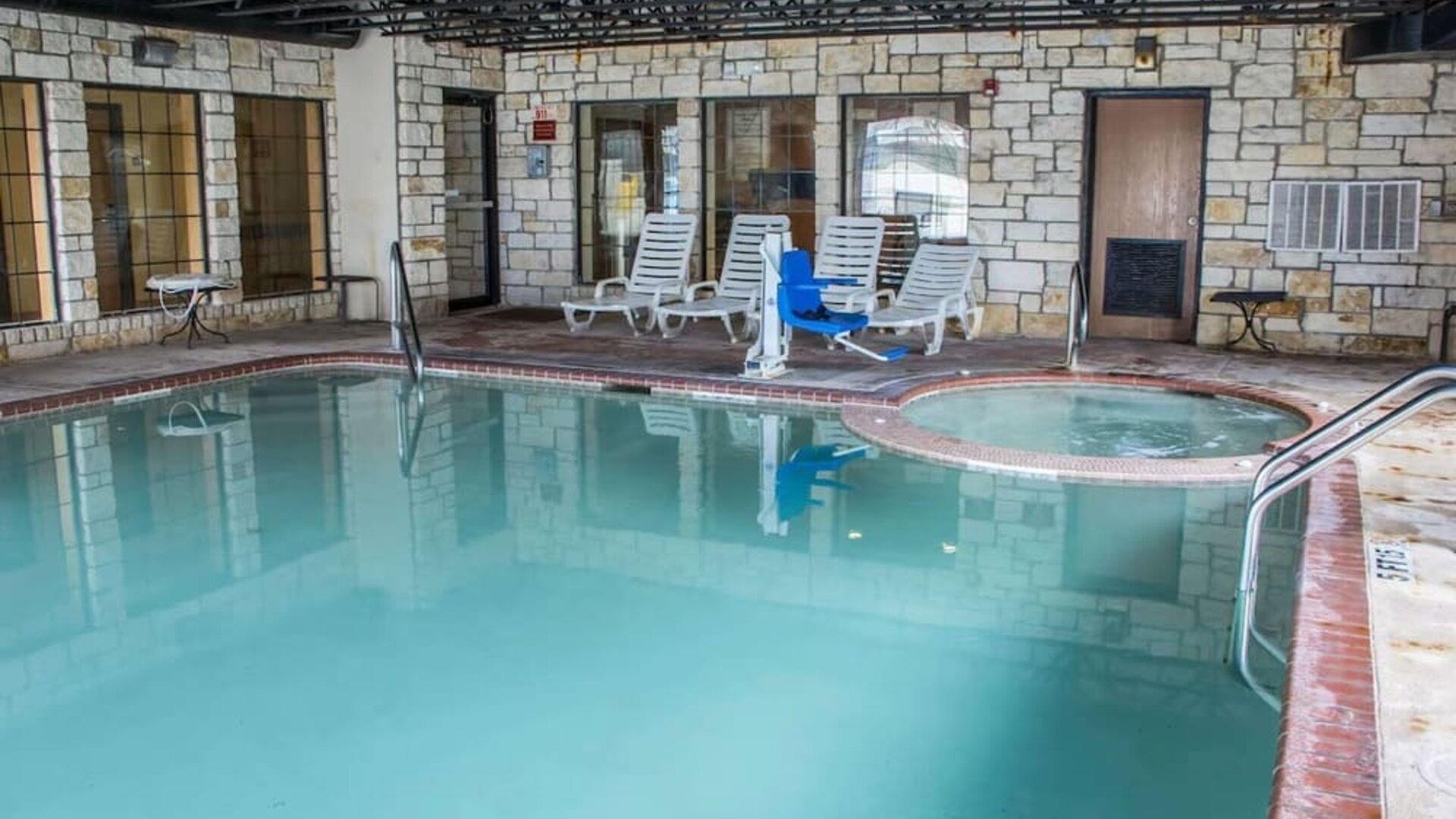 Indoor swimming pool with hot tub, lounge chairs, and accessibility lift at Comfort Suites San Antonio SeaWorld - Lackland AFB.