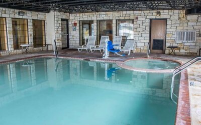 Indoor swimming pool with hot tub, lounge chairs, and accessibility lift at Comfort Suites San Antonio SeaWorld - Lackland AFB.