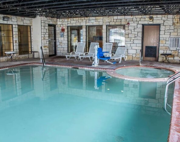 Indoor swimming pool with hot tub, lounge chairs, and accessibility lift at Comfort Suites San Antonio SeaWorld - Lackland AFB.