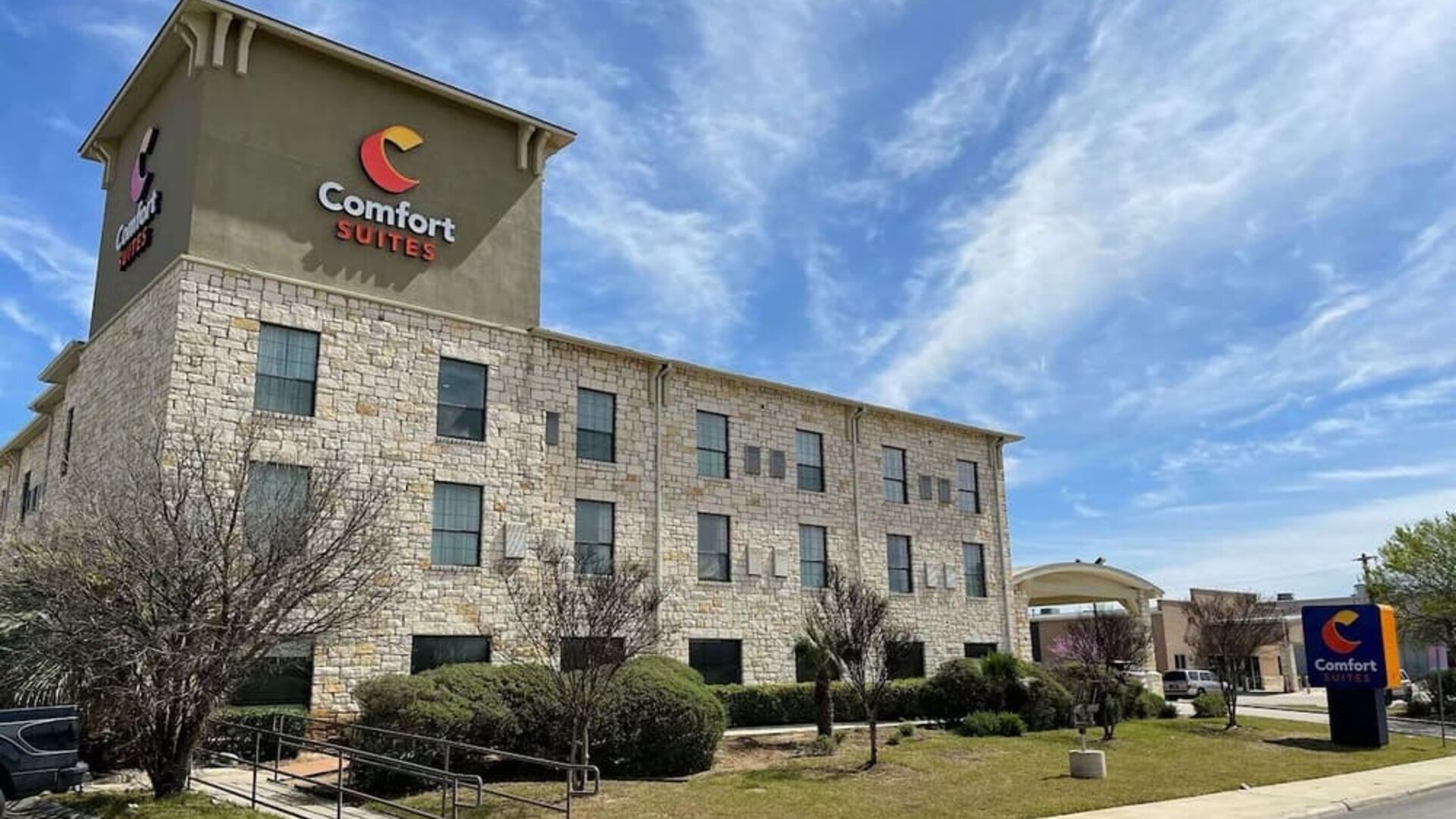 Exterior view of Comfort Suites San Antonio SeaWorld - Lackland AFB, featuring the multi-storey stone façade, landscaped grounds, and hotel signage.