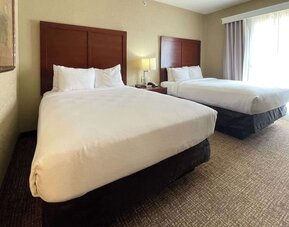 Guest room with two beds, bedside table, lamp, and natural light from a large window at Comfort Suites San Antonio SeaWorld - Lackland AFB.