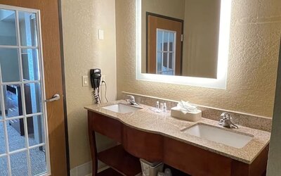 Guest bathroom with bathtub and shower, toilet, fresh towels, and tiled surround at Comfort Suites San Antonio SeaWorld - Lackland AFB.