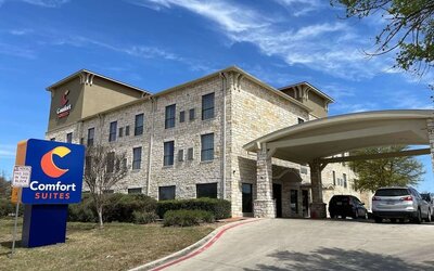 Exterior view of Comfort Suites San Antonio SeaWorld - Lackland AFB, featuring the stone façade, hotel signage, and covered entrance.