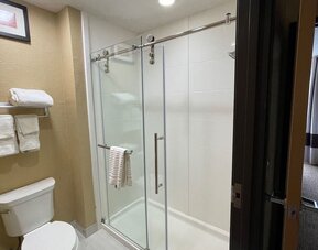 Guest bathroom with glass-enclosed walk-in shower, toilet, and fresh towels at Comfort Suites San Antonio SeaWorld - Lackland AFB.