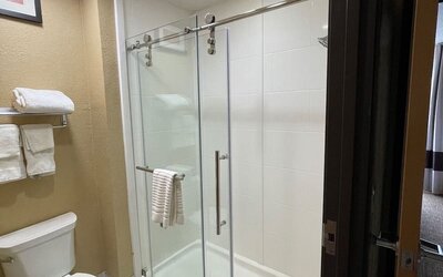 Guest bathroom with glass-enclosed walk-in shower, toilet, and fresh towels at Comfort Suites San Antonio SeaWorld - Lackland AFB.