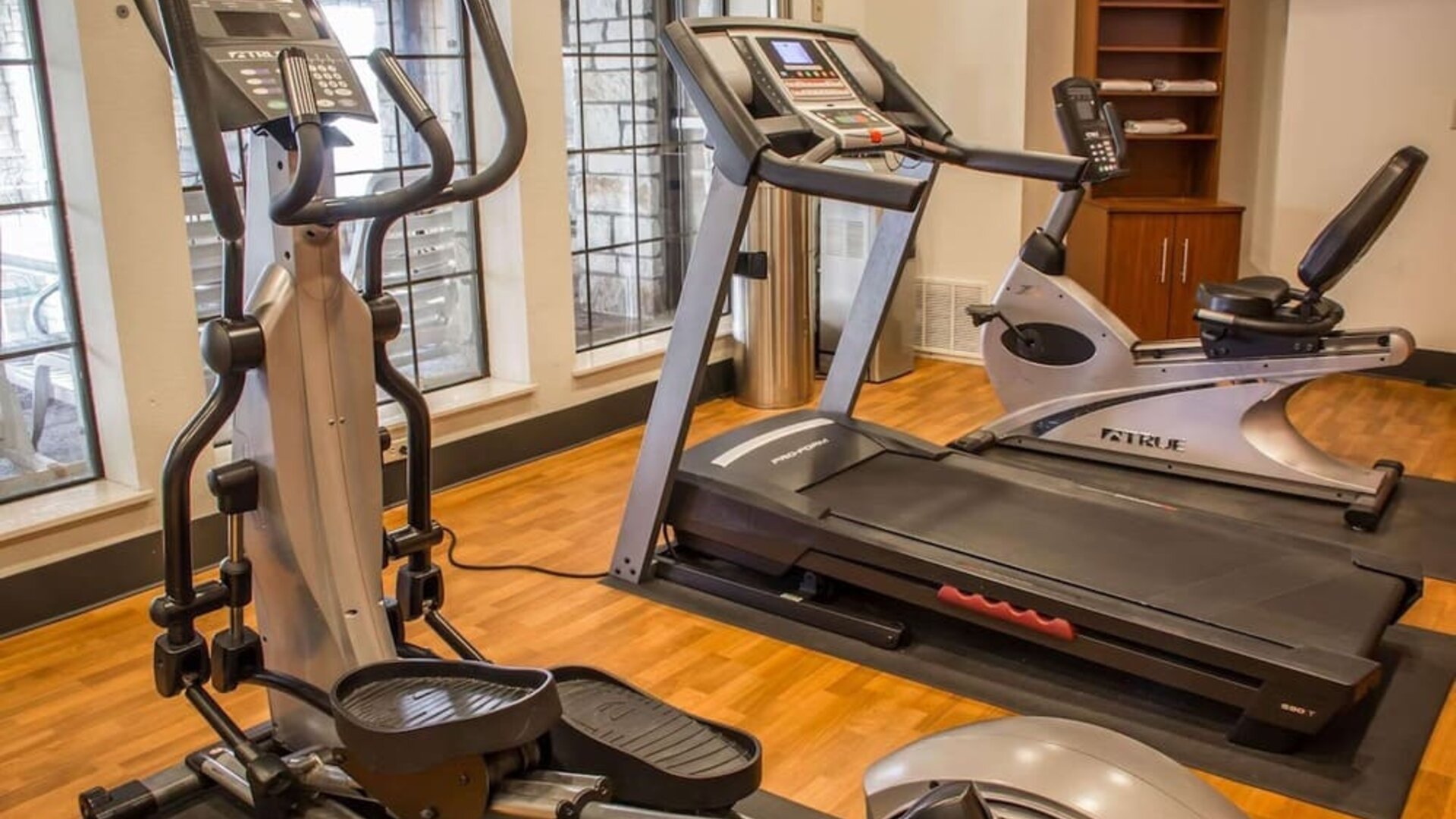 Fitness centre with treadmill, elliptical trainer, exercise bike, and large windows at Comfort Suites San Antonio SeaWorld - Lackland AFB.