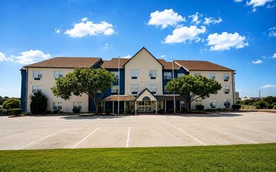 Exterior view of the hotel building, entrance, parking area, and landscaped grounds at SureStay by Best Western Lewisville Dallas.
