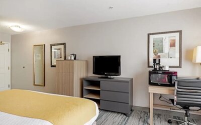 Guest room with television, dresser, microwave, coffee maker, work desk, office chair, and king bed at SureStay by Best Western Lewisville Dallas.