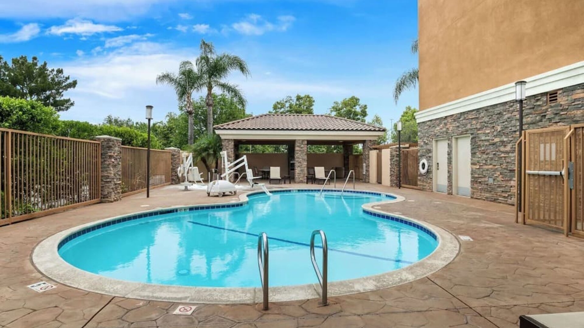 Outdoor swimming pool with lounge area and covered seating at Best Western Ontario Mills Mall.