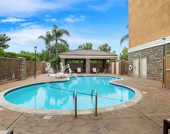 Outdoor swimming pool with lounge area and covered seating at Best Western Ontario Mills Mall.