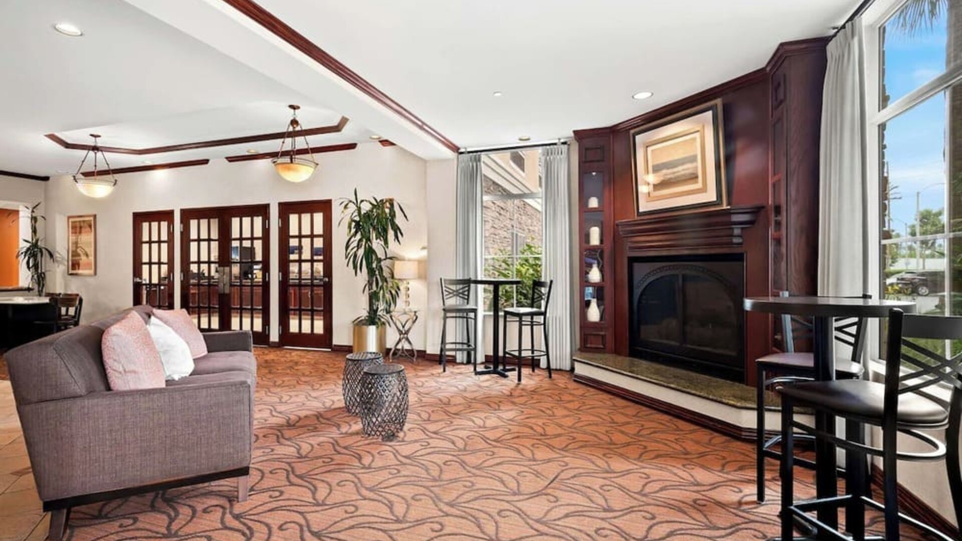 Lobby lounge with sofa seating, fireplace, high-top tables, and large windows at Best Western Ontario Mills Mall.
