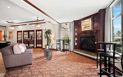 Lobby lounge with sofa seating, fireplace, high-top tables, and large windows at Best Western Ontario Mills Mall.