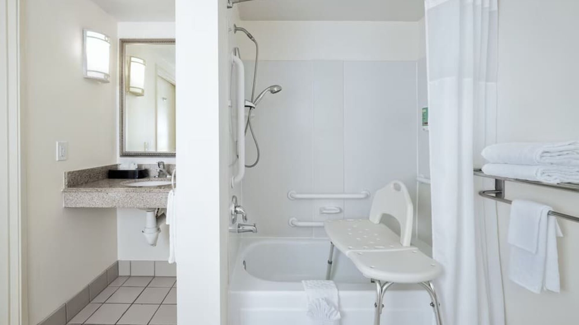 Accessible bathroom with bathtub, shower seat, grab bars, vanity, and mirror at Best Western Ontario Mills Mall.