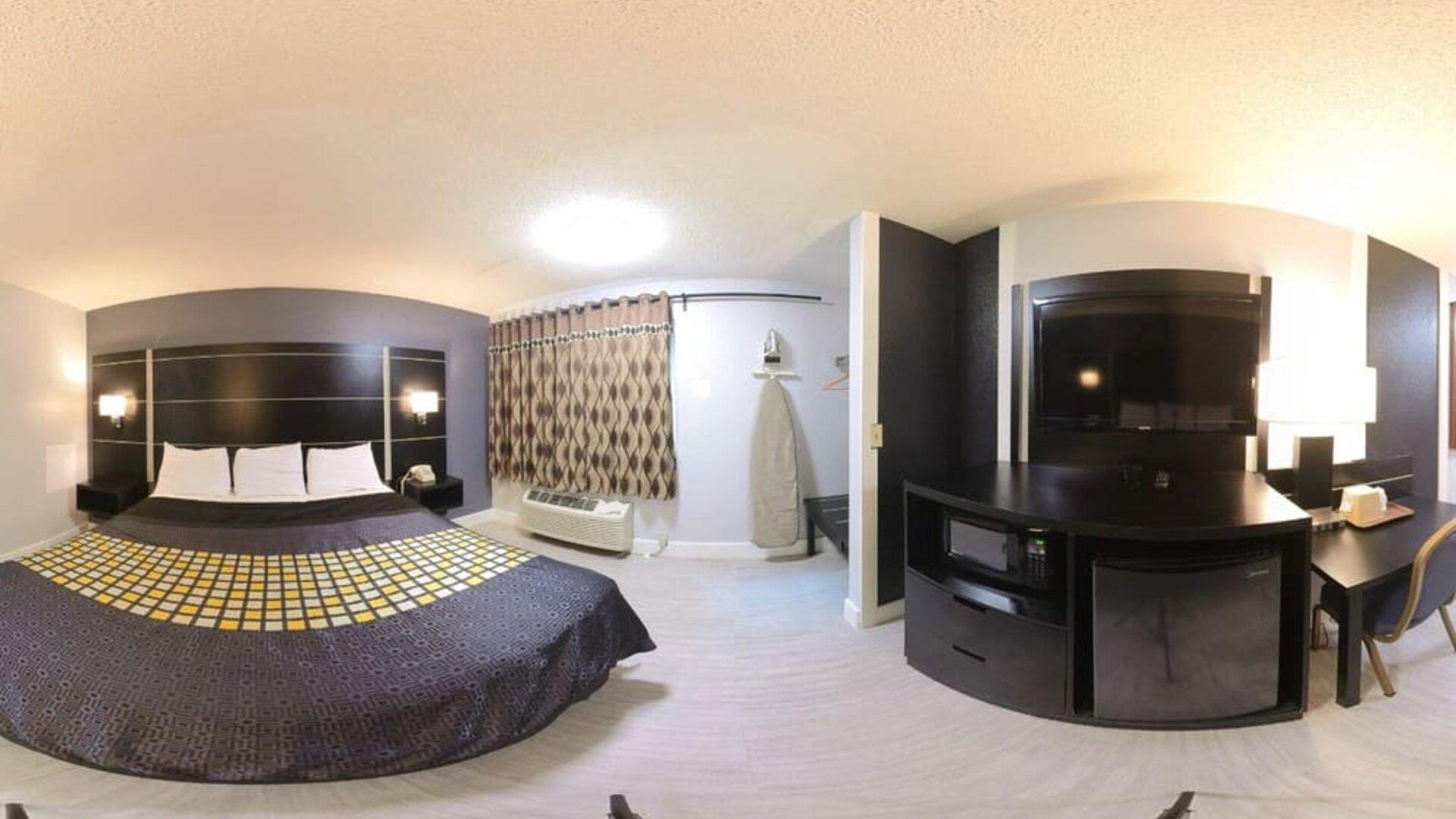 Spacious king guest room with television, microwave, mini refrigerator, work desk, and window at Coratel Inn & Suites By Jasper Hastings.