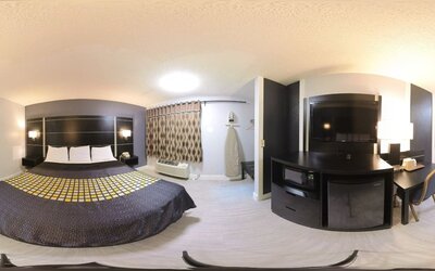 Spacious king guest room with television, microwave, mini refrigerator, work desk, and window at Coratel Inn & Suites By Jasper Hastings.