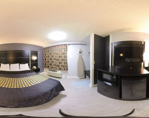 Spacious king guest room with television, microwave, mini refrigerator, work desk, and window at Coratel Inn & Suites By Jasper Hastings.