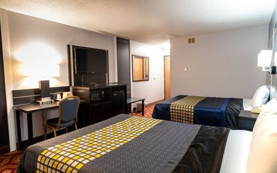 Guest room with two beds, patterned bedding, work desk, television, microwave, and mini refrigerator at Coratel Inn & Suites By Jasper Hastings.