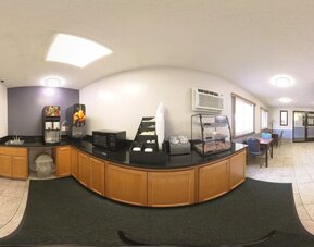 Breakfast area with beverage dispensers, microwave, pastry display, and dining tables at Coratel Inn & Suites By Jasper Hastings.