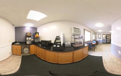 Breakfast area with beverage dispensers, microwave, pastry display, and dining tables at Coratel Inn & Suites By Jasper Hastings.