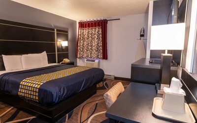 King guest room with patterned bedding, work desk, window, and in-room ironing facilities at Coratel Inn & Suites By Jasper Hastings.